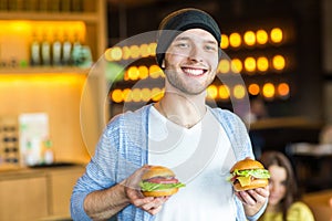 Man in hands holds a burger. Man eating a burger at the cafe