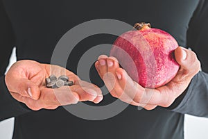 Man hands with iron supplements and pomegranates to treat iron deficiency anemia photo