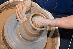 Man hands making ceramic pot vase on the pottery wheel