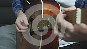 Man hands playing on acoustic guitar. Fingers strumming on acoustic guitar strings. Close up