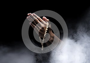 Man hands praying with prayer beads over dark background