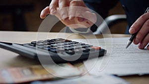 Man hands pressing calculator buttons counting tax financial bills close up.