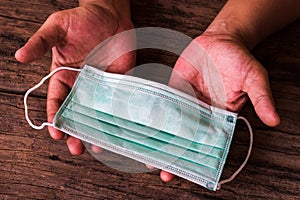 Man hands showing surgical mask on wood table.  Illustration to invite people to donate medical masks during virus diseases