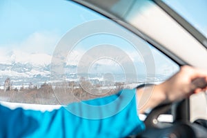 Man hands on steering wheel winter road trip