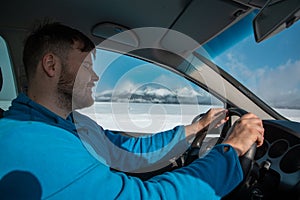 Man hands on steering wheel winter road trip