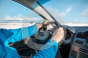 Man hands on steering wheel winter road trip