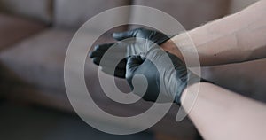 Man hands takes off black nitrile protective gloves indoors