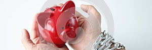 In man hands tied by chain red pig piggy bank