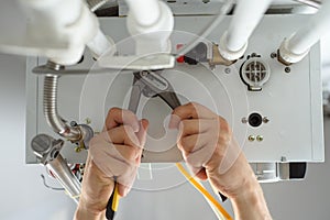 A man hands with tools check the pipes that fit the gas heating boiler