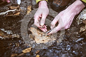 Man hands trying to make fire by flint in a forest.