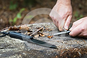 Man hands trying to start a fire with survival tools