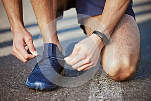 Man, hands and tying shoes for running, fitness or cardio exercise on asphalt road in the outdoors. Hand of male person