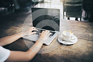 Man hands typing in laptop and coffee mug on wooden table