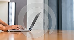 Businessman fingers typing on laptop, texting in computer on wooden table at home living room. Concept of internet online shopping