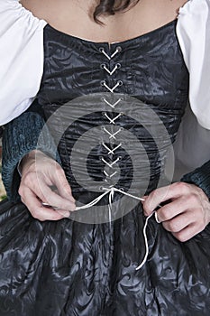 Man hands untying corset of woman in medieval dress