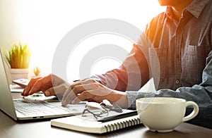 man hands using keyboard of laptop computer on office desk.