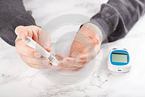 Man hands using lancet on finger to check blood sugar or ketones level by glucose meter. medicine diabetes keto diet health care photo