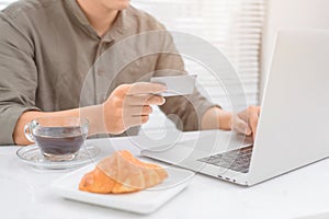 Man hands using laptop and holding credit card in morning light