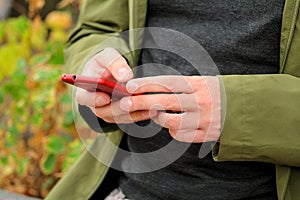 Man hands using mobile cell phone outdoors. Social media concept. Closeup of male hand holding and using modern smartphone.
