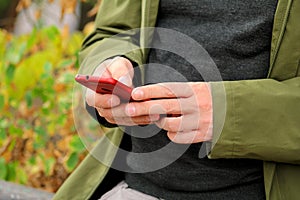 Man hands using mobile cell phone outdoors. Social media concept. Closeup of male hand holding and using modern smartphone.