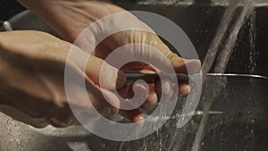 man hands washing a metal knife with a sponge a close-up shot lifestyle sun