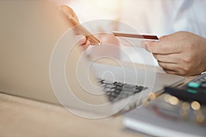 Man hands in white shirt sitting and holding credit card and using laptop computer on table for online payment or shopping online