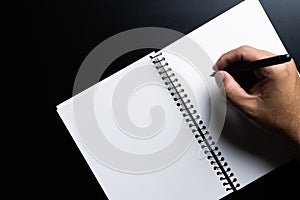 Man hands writing on book in office.Business Man working on desk of black material