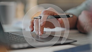 Man hands writing in notebook at desk close up. Man working online using laptop.