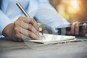Man hands writing notebook diary with coffee cup and smartphone on wood desk. Close up man hands using pen sitting at wooden table