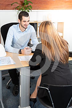 Man handsome boss looking at young girl manager with smile while listening to her explanations of report