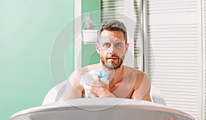 Man handsome muscular guy relaxing in bath. Pampering and beauty routine. Skin care concept. Taking bath with soap suds