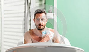 Man handsome muscular guy relaxing in bath. Pampering and beauty routine. Skin care concept. Taking bath with soap suds