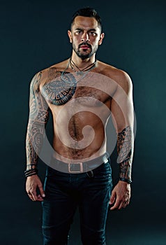 Man handsome shirtless muscular with jeans over dark background. Muscular tattooed athlete look attractive. Sport and