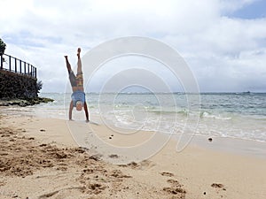 Man Handstand on beach as wave roll into Shore