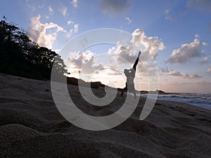 Man Handstanding on beach at sunset as wave crash