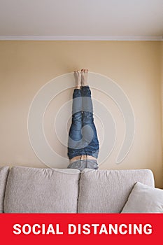 Man handstanding behind couch. People goes crazy in quarantine