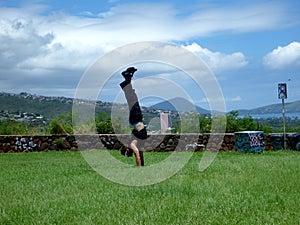 Man handstands in grass field on top of Kaimuki