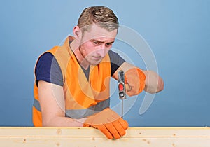 Man, handyman in working uniform and protective gloves handcrafting, light blue background. Carpenter, woodworker