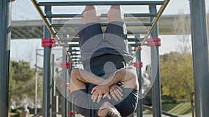 Man hanging on monkey bar and working out abs