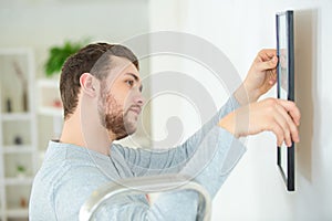 Man hanging picture frames on wall at home