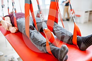 Man hanging on the suspension equipment during the spine treatment