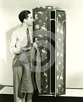 Man hanging up blazer in armoire photo