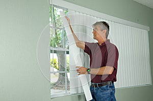 Man hanging vertical blinds home repair maintenance