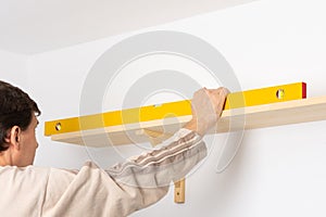 A man hangs a shelf in an apartment