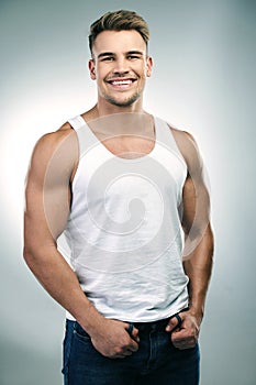 Man, happy and portrait in white background or funny with humour while joking in a tank top, fashion and wellness for