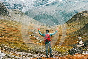 Man happy raised hands with backpack exploring mountains