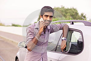 Man happy talking on the phone leaning on the door of his car