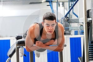Man hard working his back on hyperextension bench.