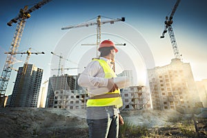 Man in hardhat and green jacket posing on building site
