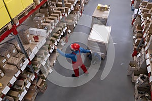 Man in hardhat working with pallet truck at warehouse, above view. Logistics center